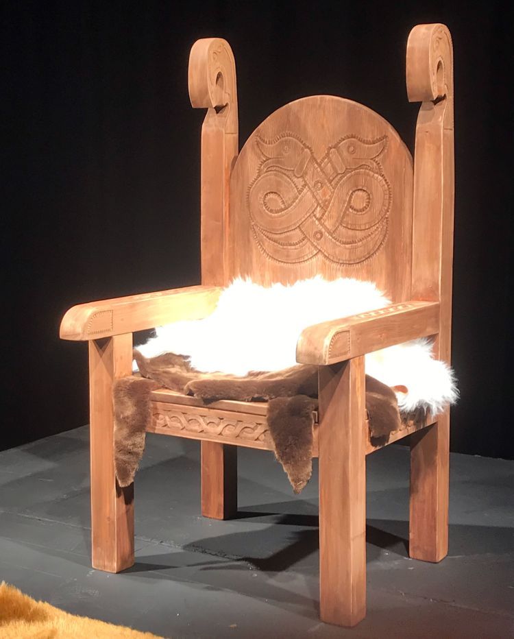 Large wooden viking-style chair with white fake fur throw